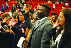 A candidate for U.S. citizenship raises his right hand during the Oath of Allegiance April 23 at the Natural- ization Ceremony of 526 individuals from 97 different countries. Photo by Maggie Cipriano.