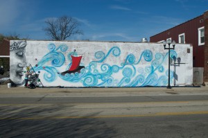 A local artist and bar owner, Jessica McGhee, works on a street mural on West Main Street. The piece aims to represent the diversity throughout businesses in the neighborhood. Photo by Moira Nolan.